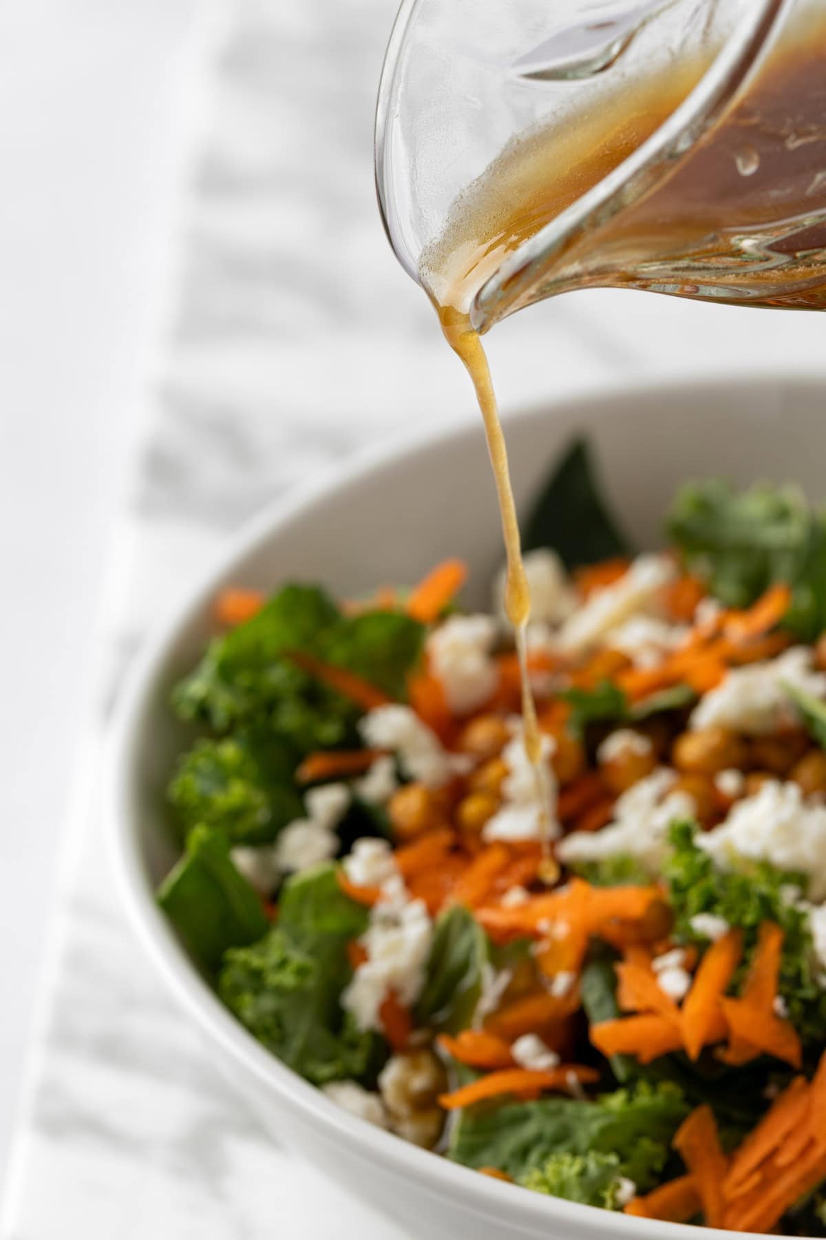 Pouring the citrus vinaigrette on to a leafy green salad.