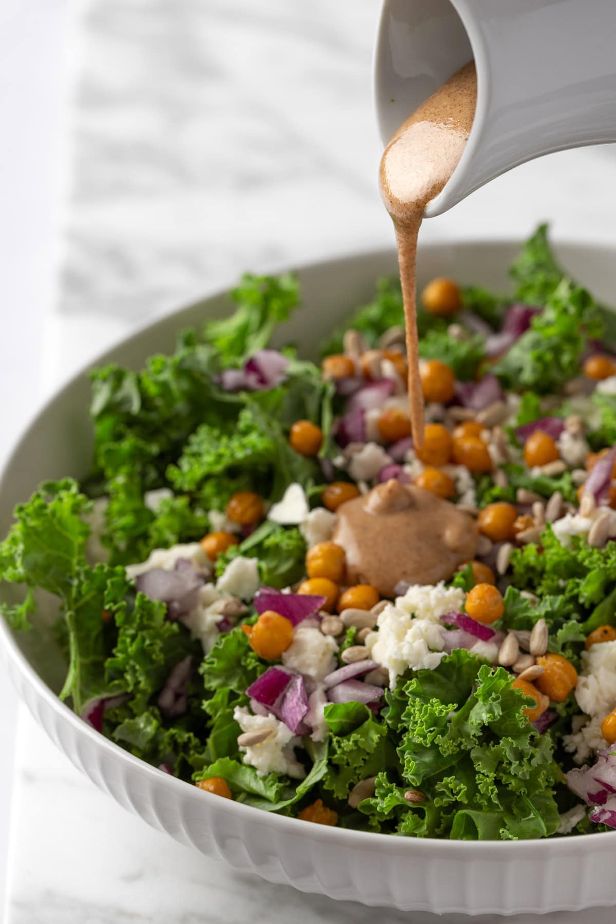 Pouring the balsamic date vinaigrette onto a salad.