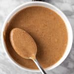 Overhead view of a spoonful of Balsamic Date Vinaigrette in a white bowl.