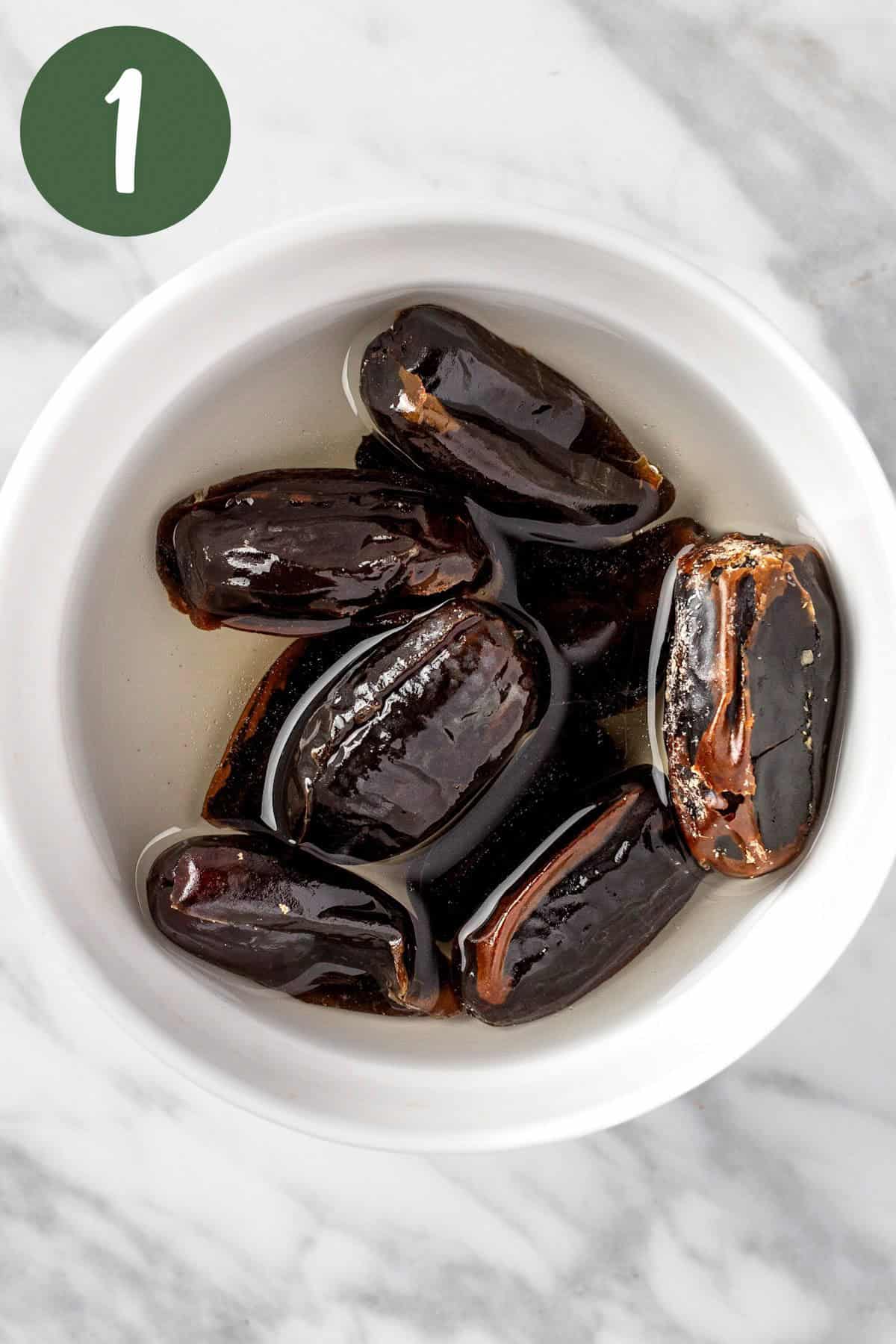 Soaking the dates in water in a white bowl.