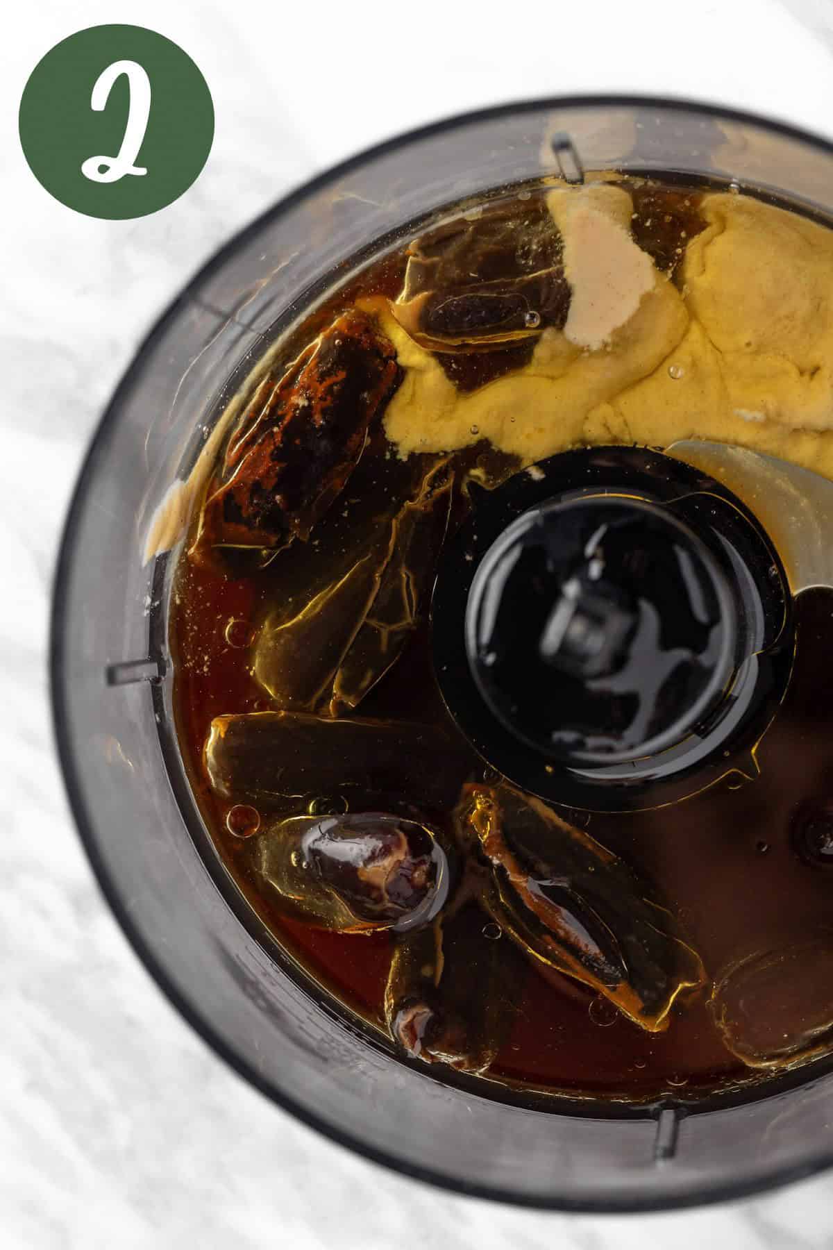 Overhead view of the dates, tahini, balsamic vinegar and olive oil in a food processor.