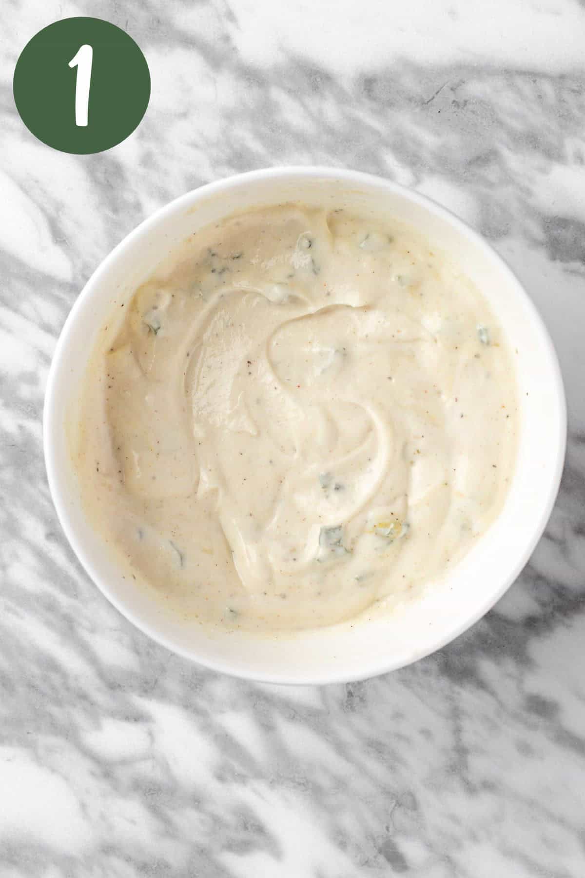 The creamy dressing ingredients mixed together in a small, white bowl.
