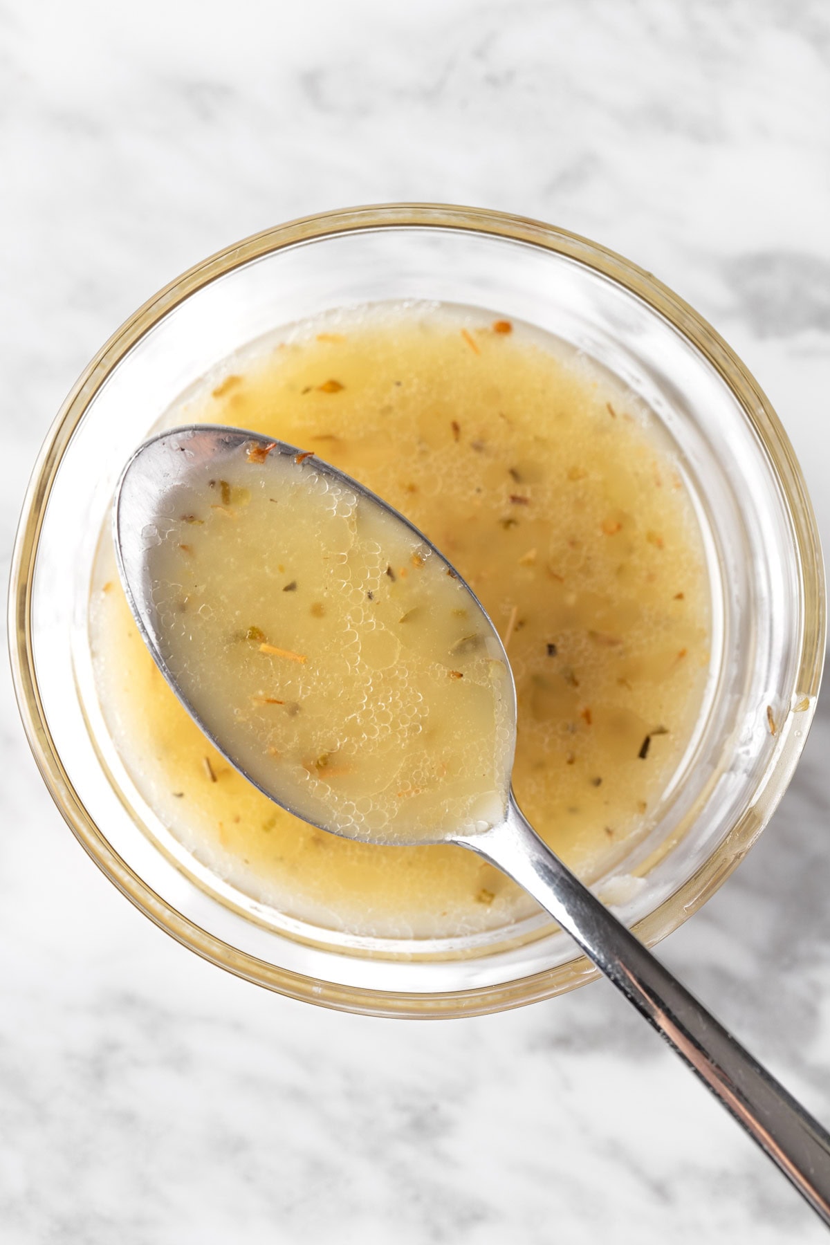 A spoonful of lemon oregano vinaigrette in a small glass bowl.
