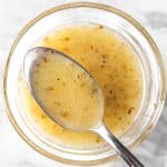 A spoonful of lemon oregano vinaigrette in a small glass bowl.