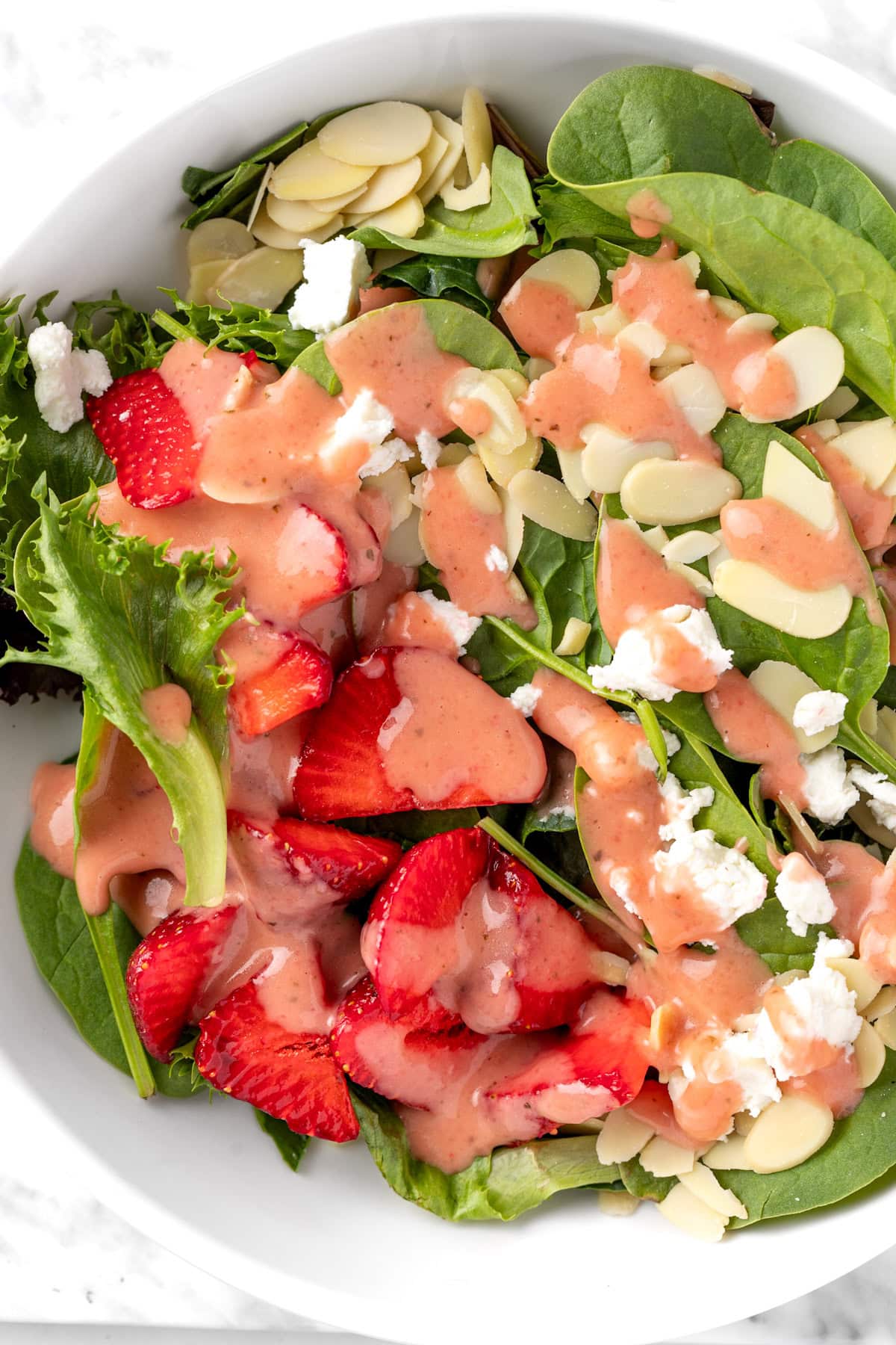 A spinach, strawberry, almond and goat cheese salad topped with strawberry basil vinaigrette.