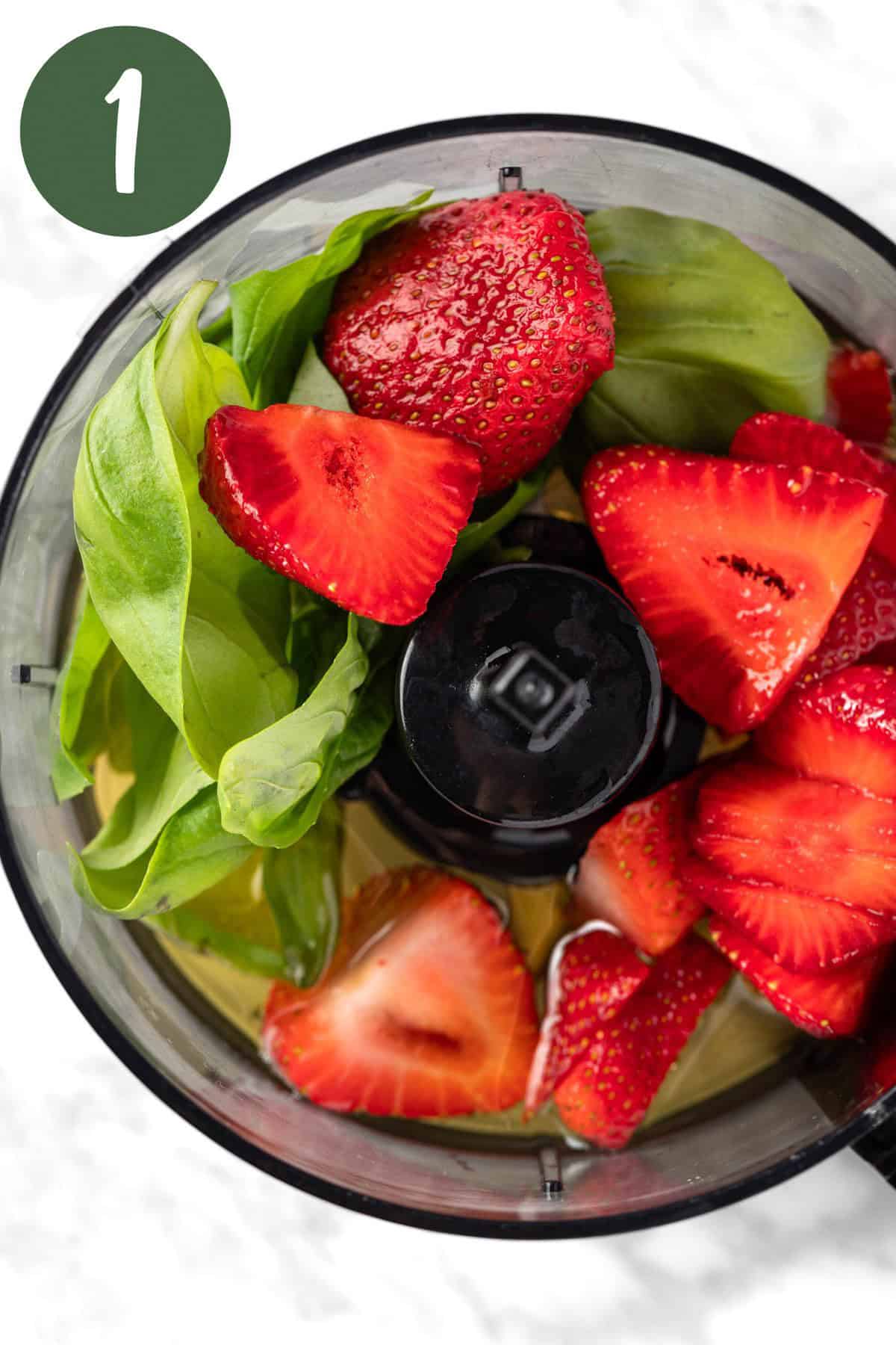 Strawberries, basil and other dressing ingredients in a food processor, before being blended.