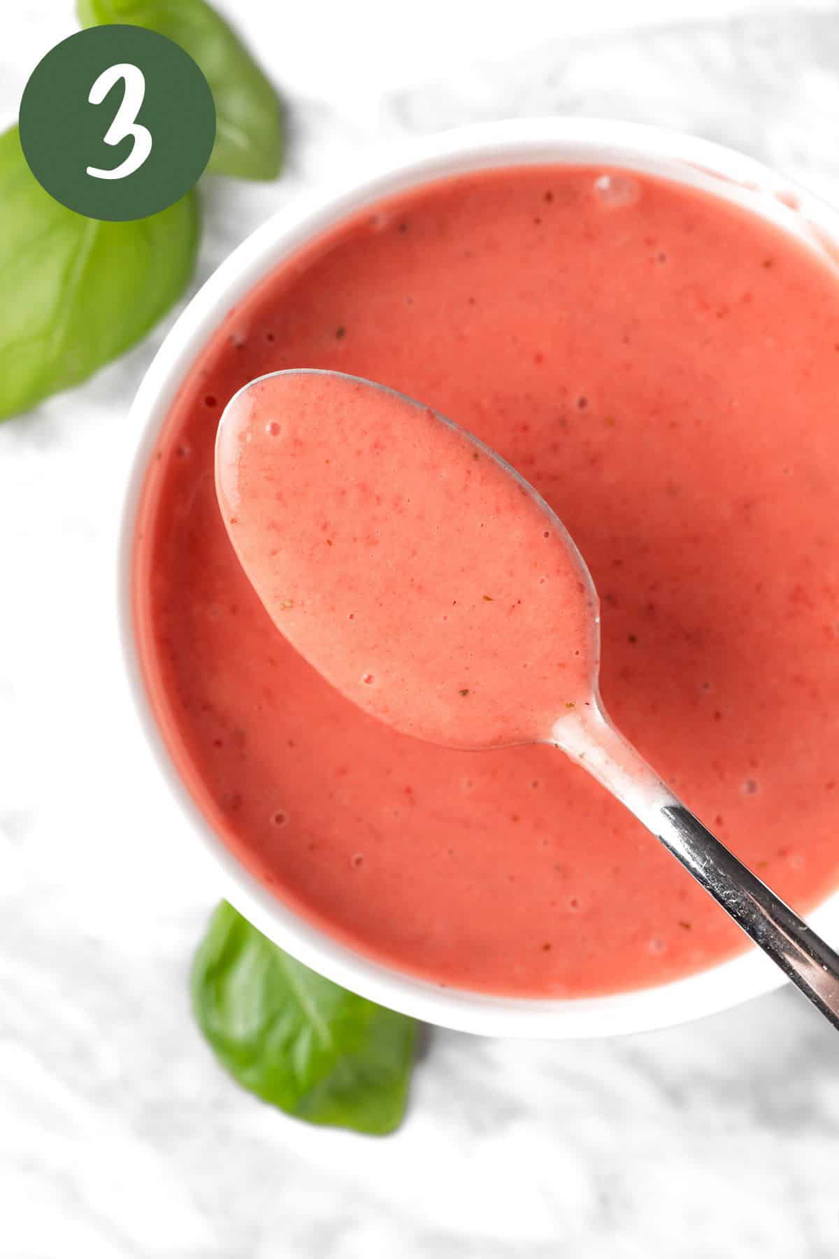 A spoonful of pink strawberry basil vinaigrette dressing.