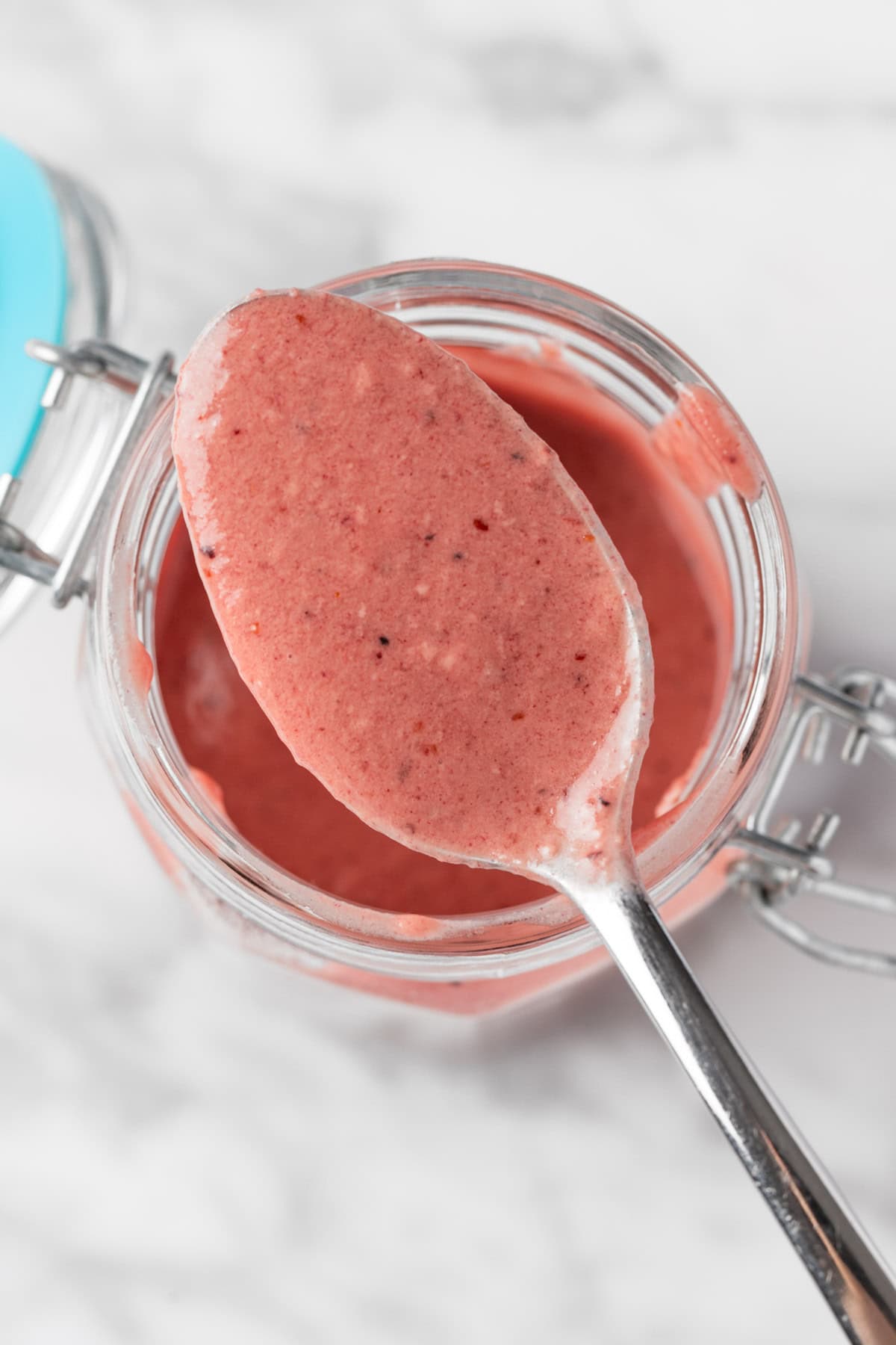 A spoonful of Blueberry Balsamic Vinaigrette on a white table.
