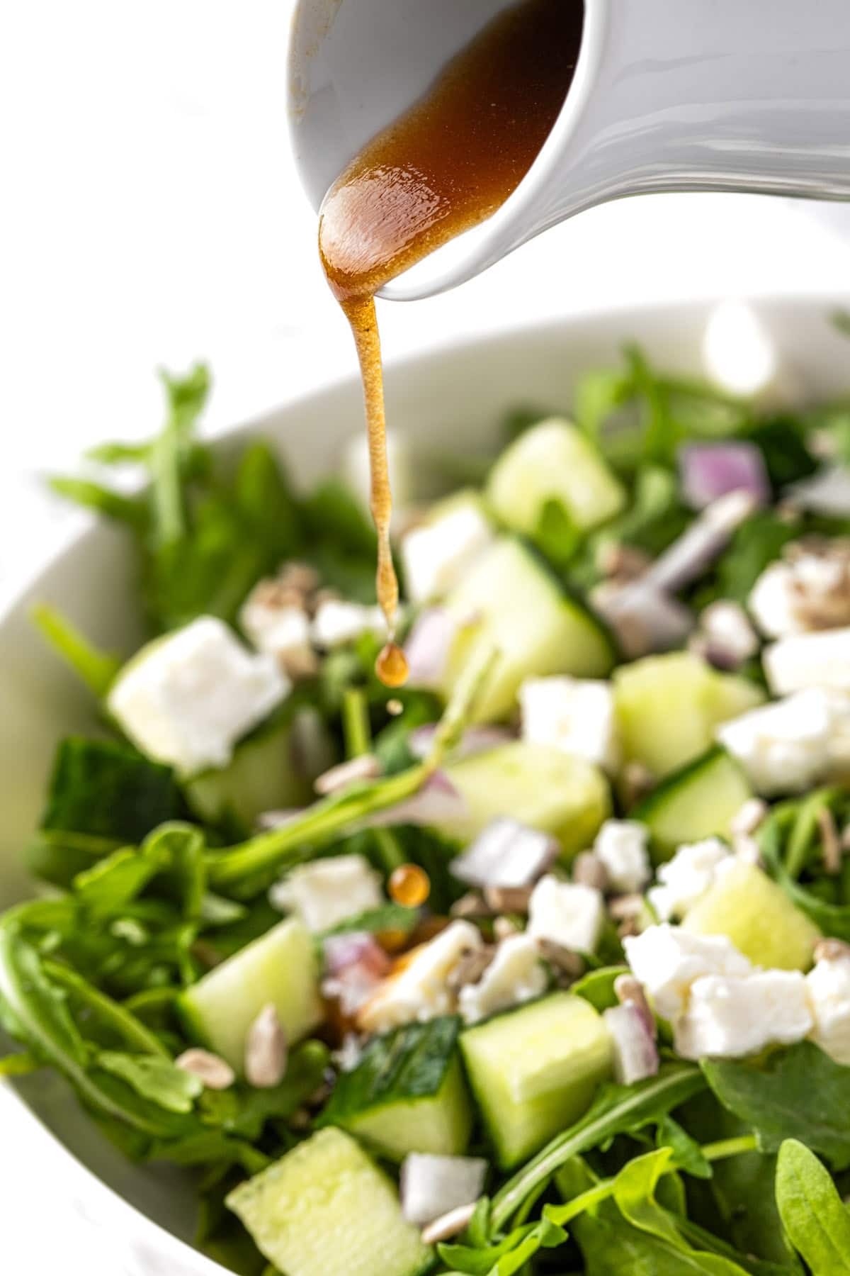 Sweetgreen balsamic vinaigrette being poured over a green salad.