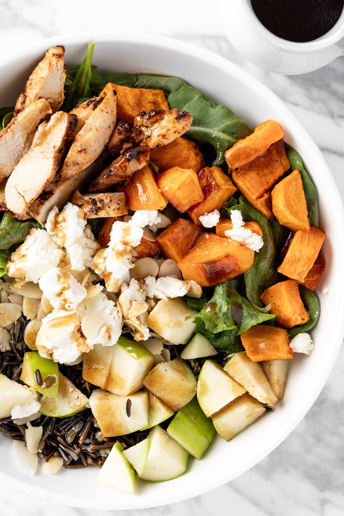 Overhead view of a Sweetgreen Harvest Bowl salad with goat cheese, wild rice, sweet potatoes, kale, chicken and apple.