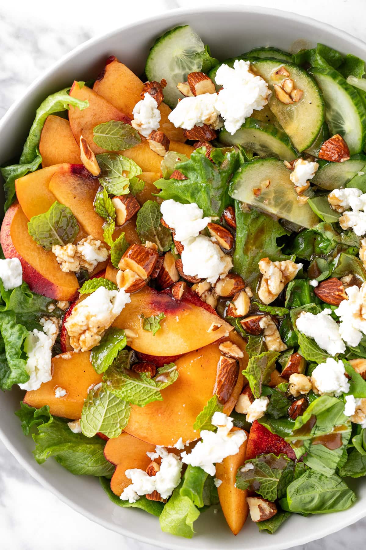 A Sweetgreen peach and goat cheese salad with basil, mint and almonds.