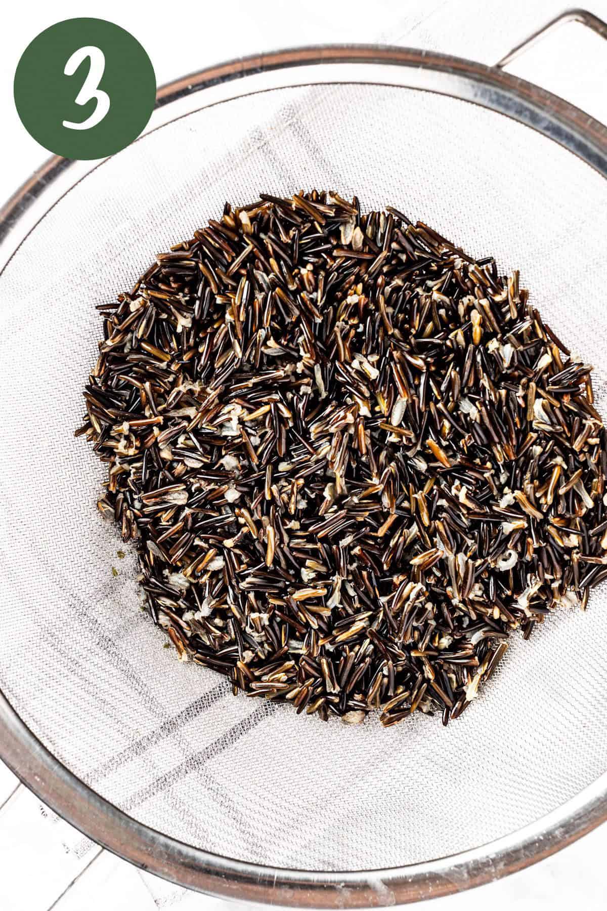 Draining the wild rice in a large strainer.