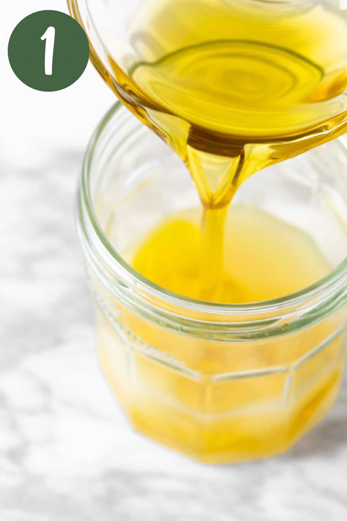 Pouring the olive oil into a mason jar with the rest of the vinaigrette ingredients.