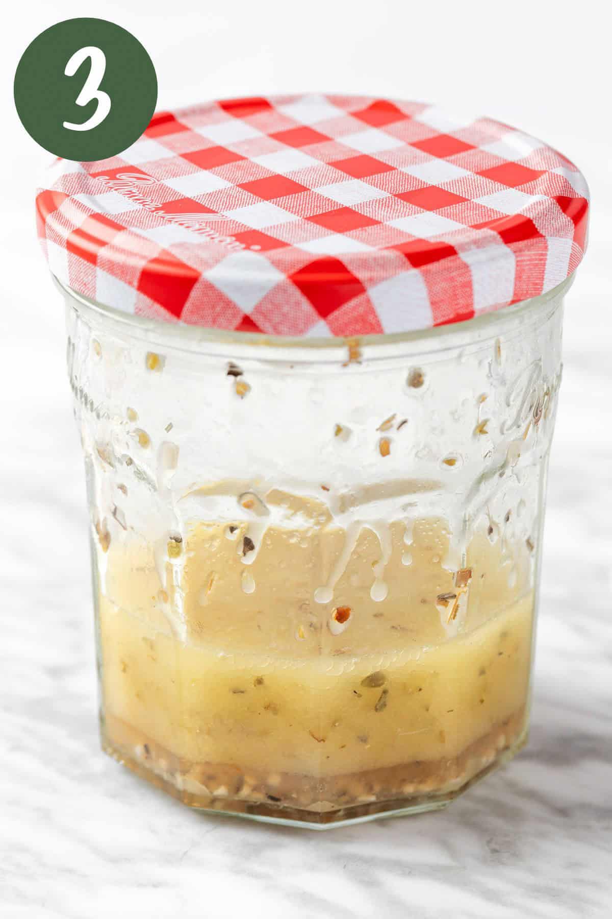 Mixing the lemon oregano vinaigrette together in a mason jar.