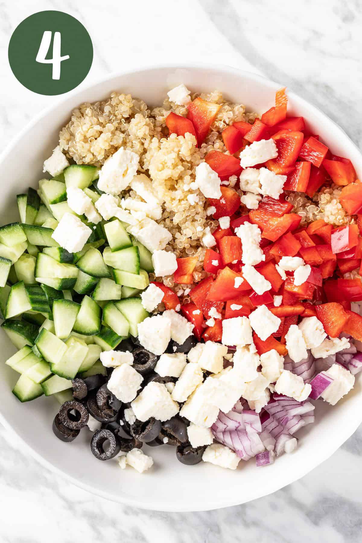 A bowl of Mediterranean salad with olives, feta, red onion, red bell pepper, cucumber and quinoa.