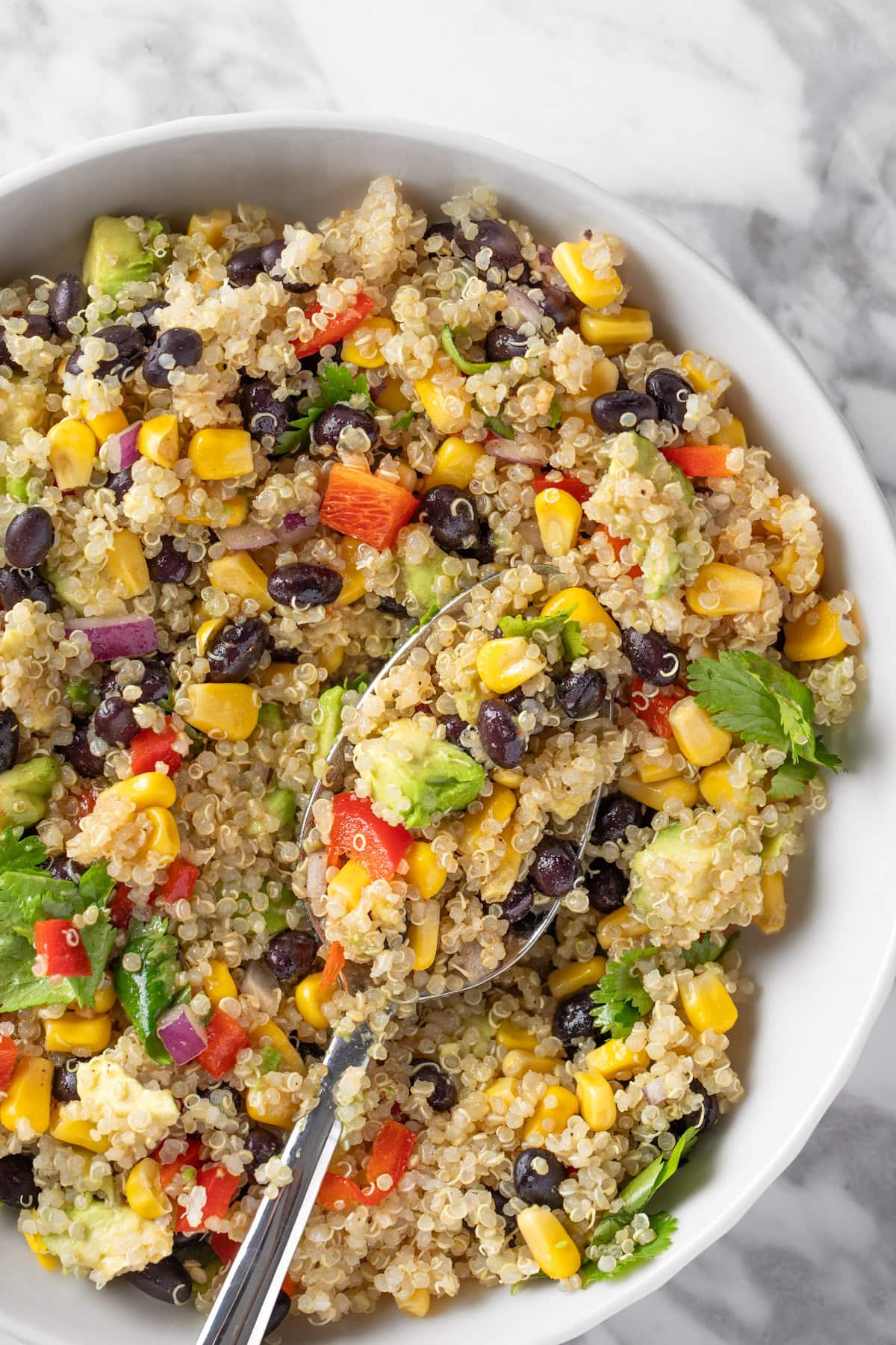 A white bowl on a grey countertop of Southwestern Quinoa Salad made with corn, black beans, cilantro and red pepper.