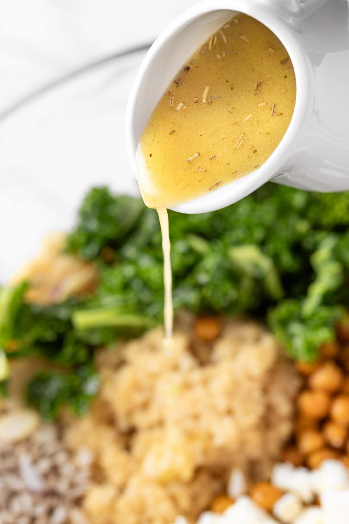 Pouring the lemon dijon vinaigrette over a quinoa salad.