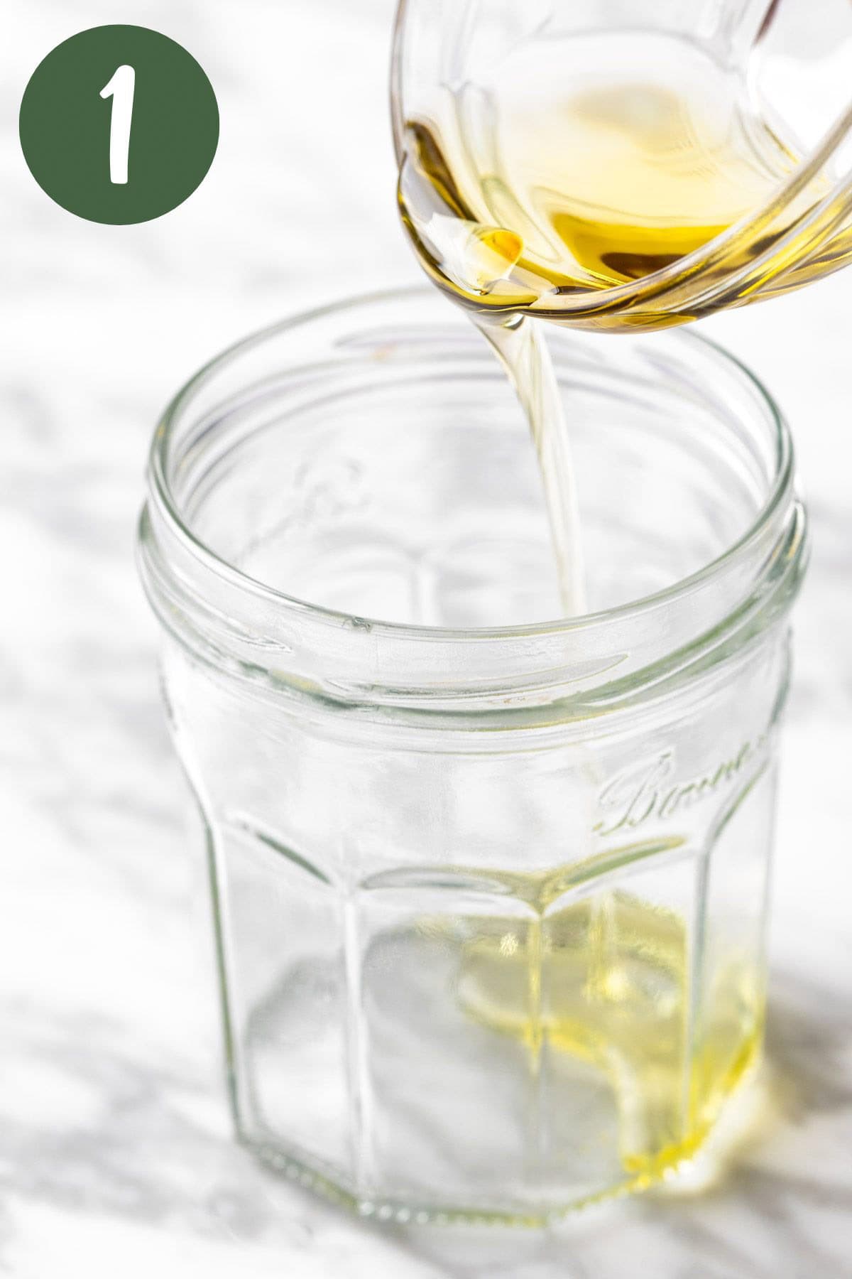 Pouring the olive oil into a mason jar.