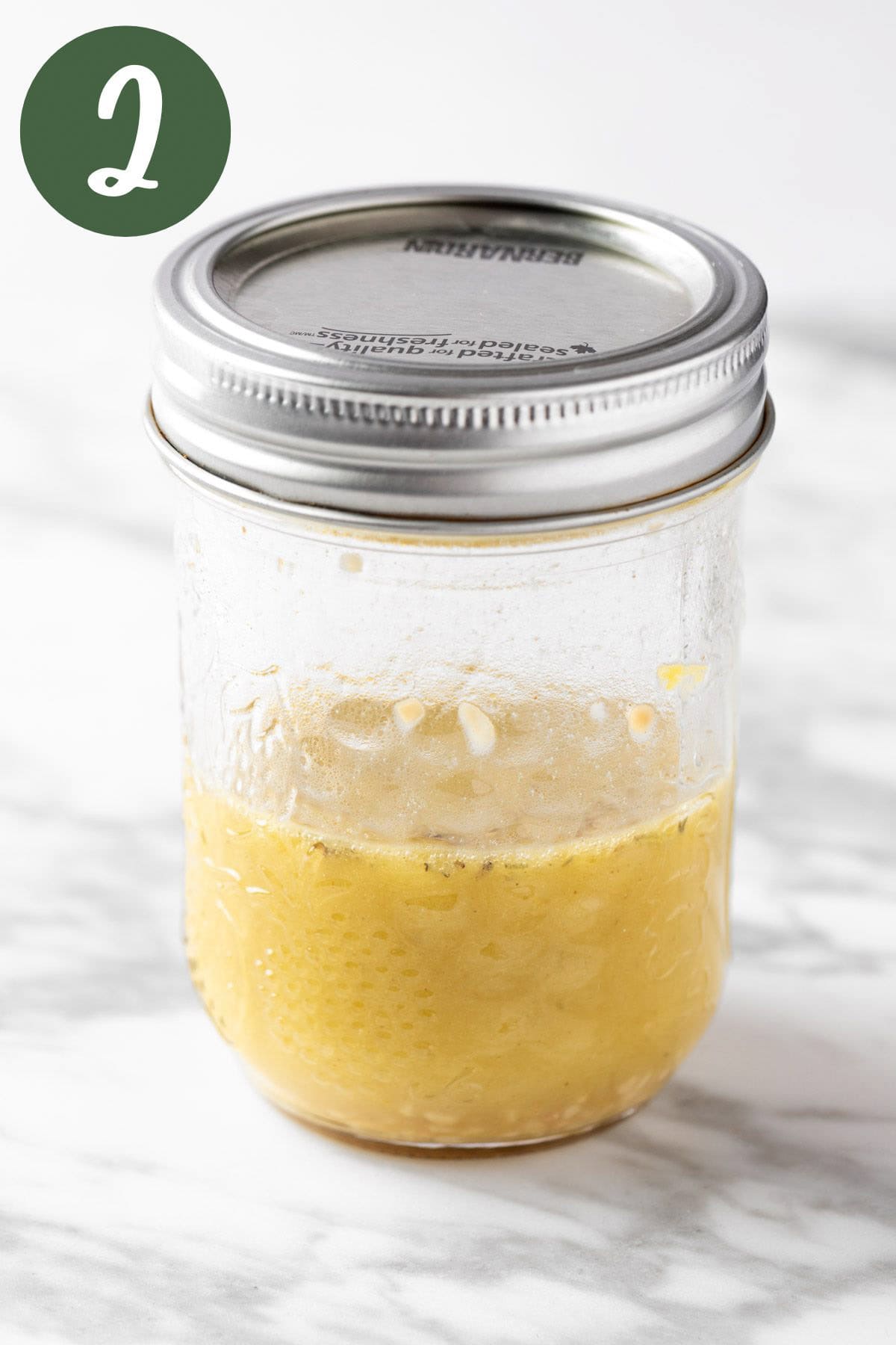 Mixing the salad dressing ingredients together in a mason jar.