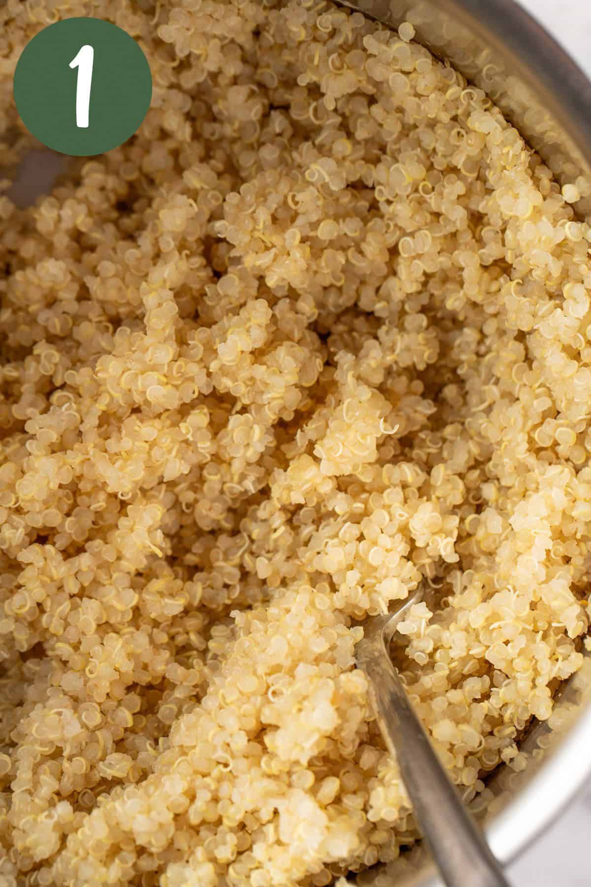 Fluffing the freshly cooked quinoa in a saucepan with a fork.