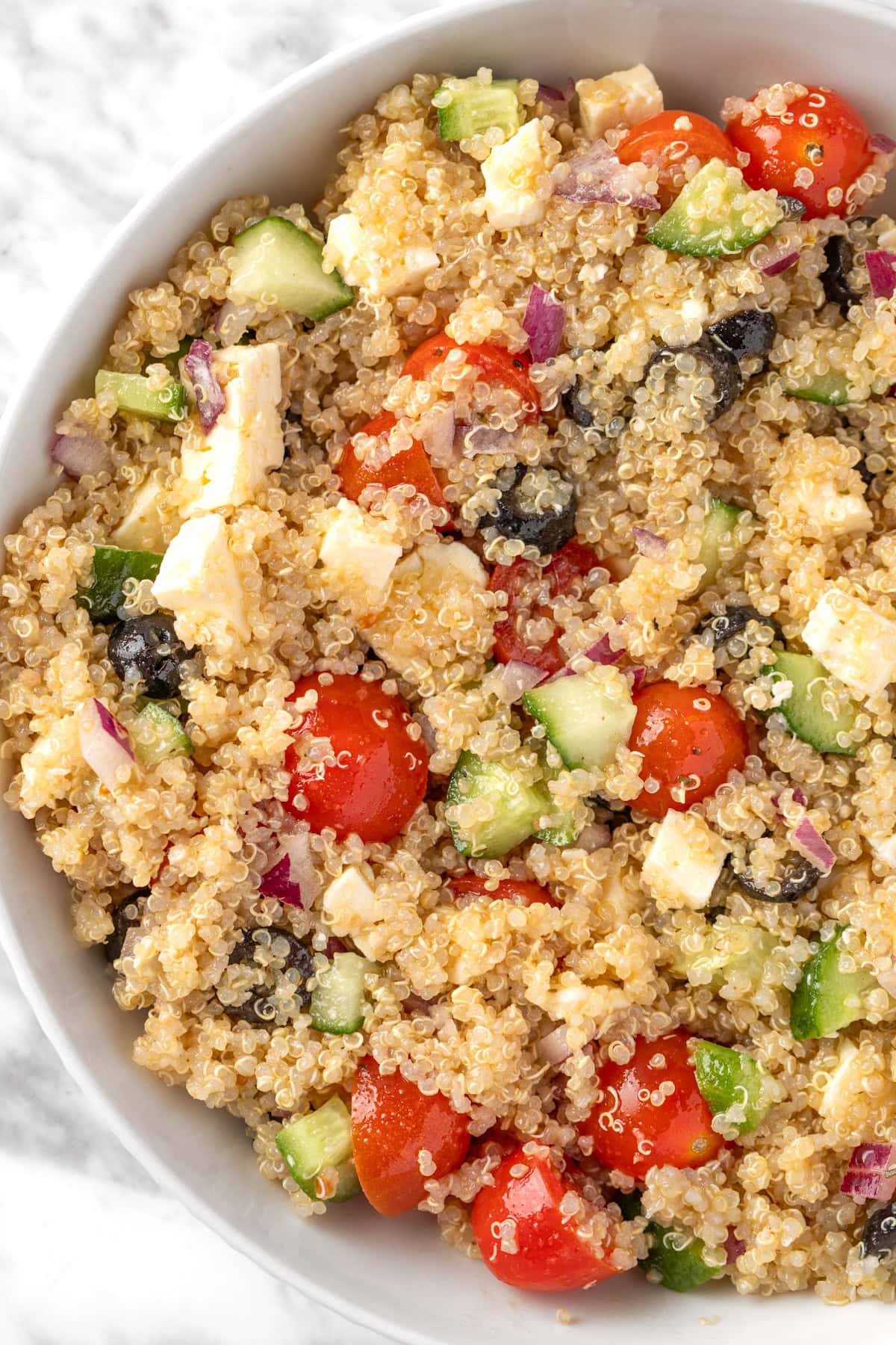 Overhead view of a bowl of Greek Quinoa Salad made with cucumbers, cherry tomatoes, feta, olives and red onion.