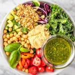 A bowl of Sweetgreen Hummus Crunch salad made with cherry tomatoes, chickpeas, basil leaves, kale, red cabbage, cucumbers, za’atar bread crumbs, hummus and pesto vinaigrette.