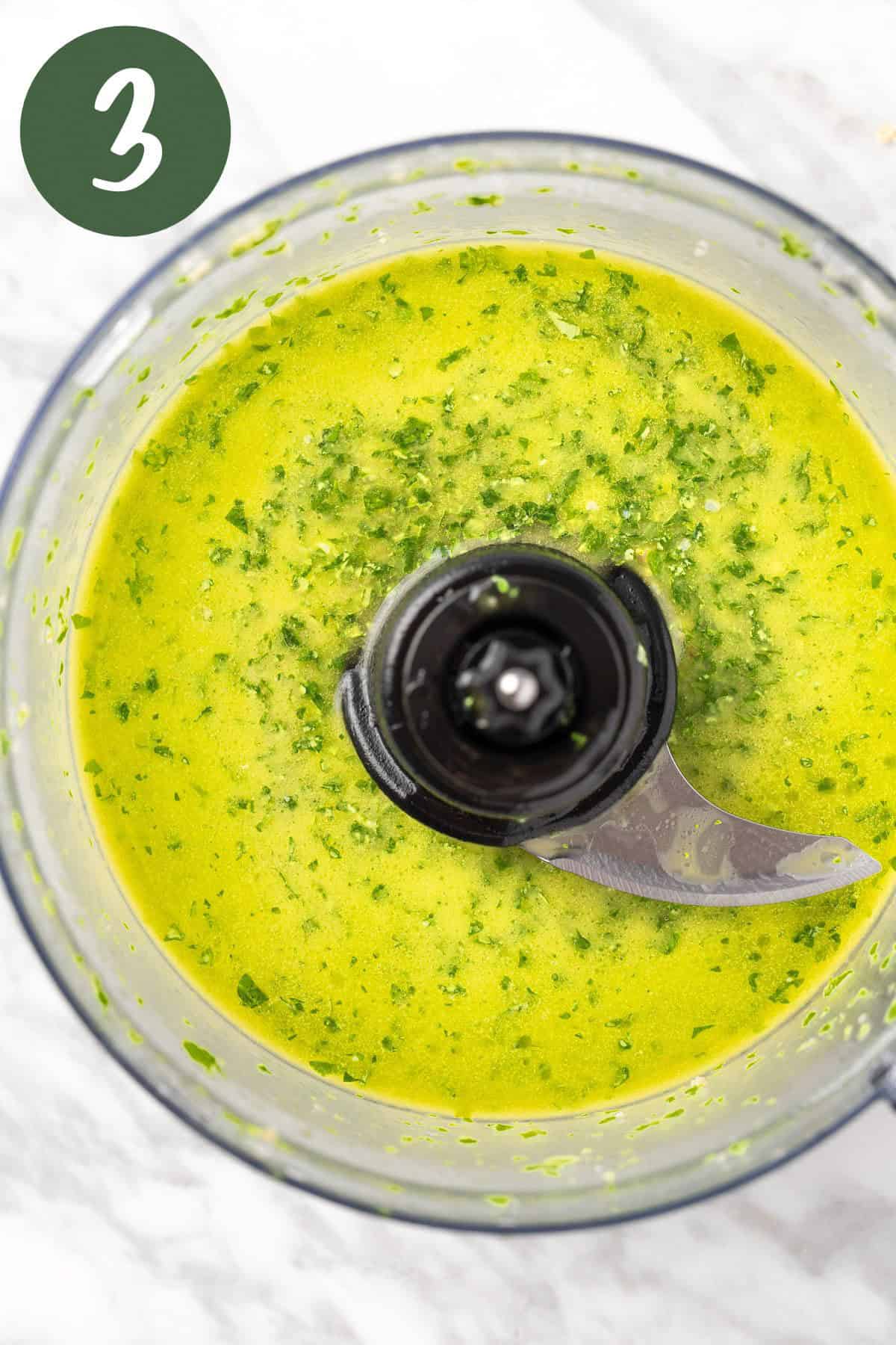 A process photo of the emulsified pesto vinaigrette in a food processor.