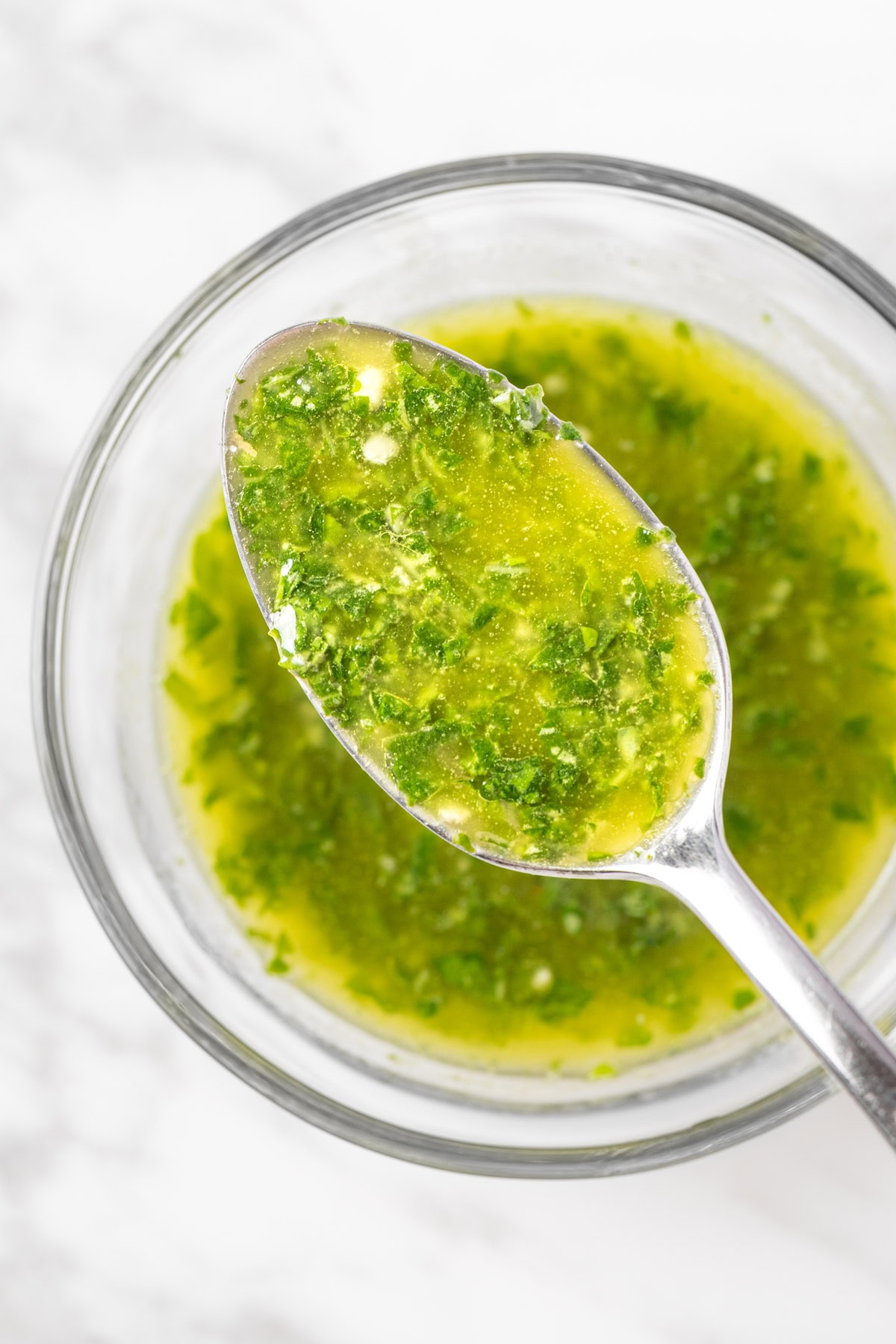 An up close spoonful of Sweetgreen pesto vinaigrette made with fresh basil and olive oil.
