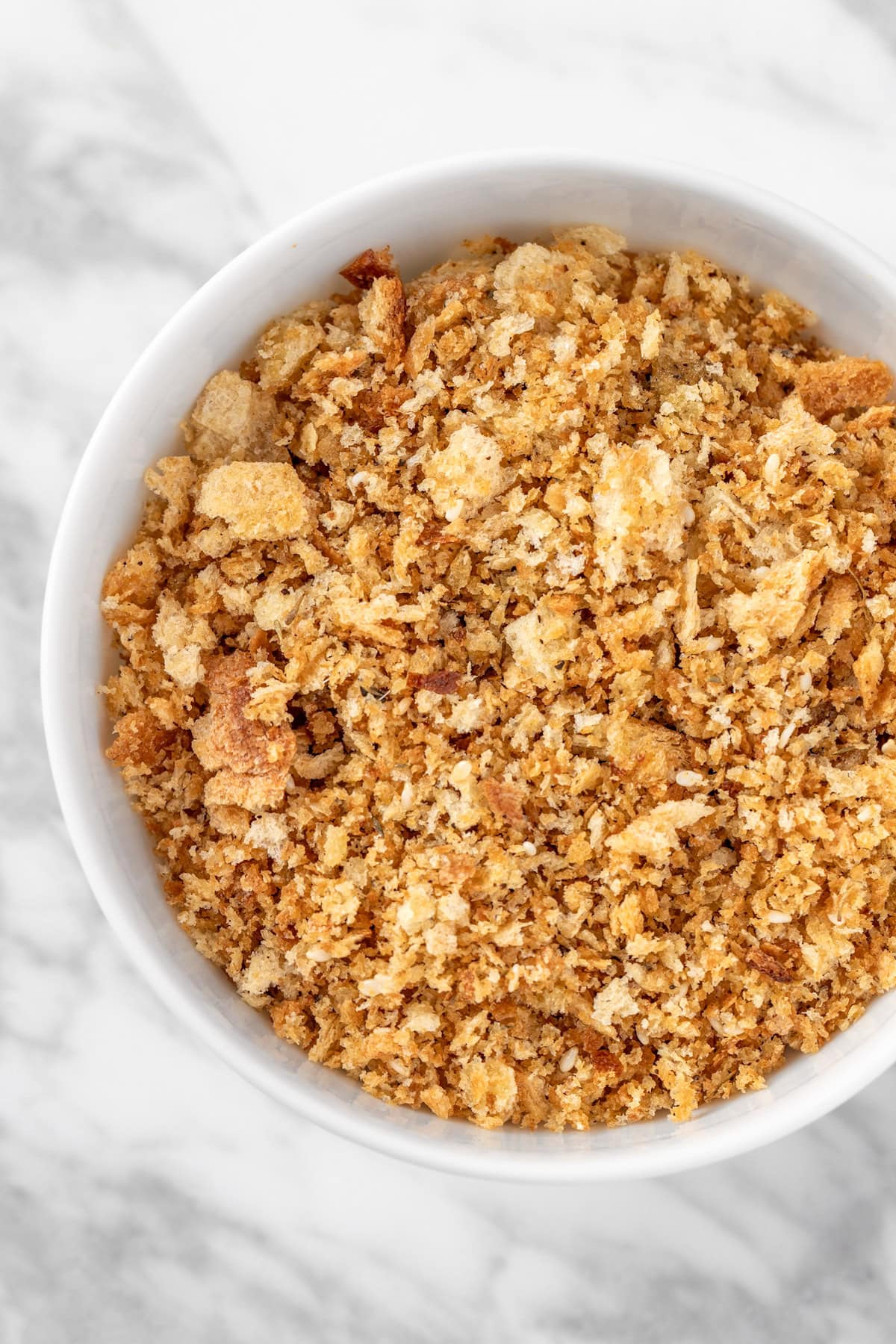A white bowl on a marble table filled with golden Sweetgreen za’atar bread crumbs.