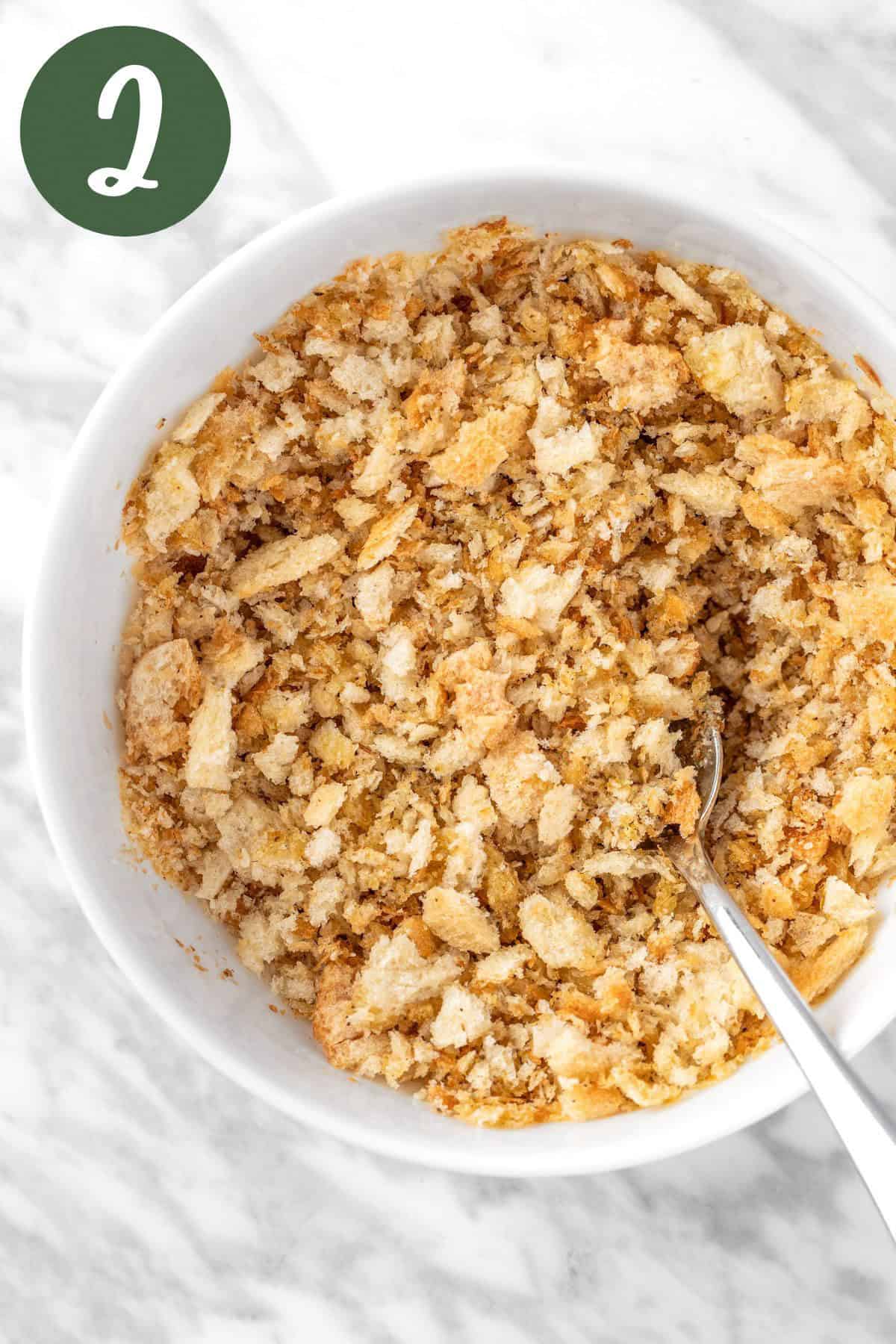 A process photo showing a bowl of breadcrumbs coated with olive oil and za’atar seasoning.