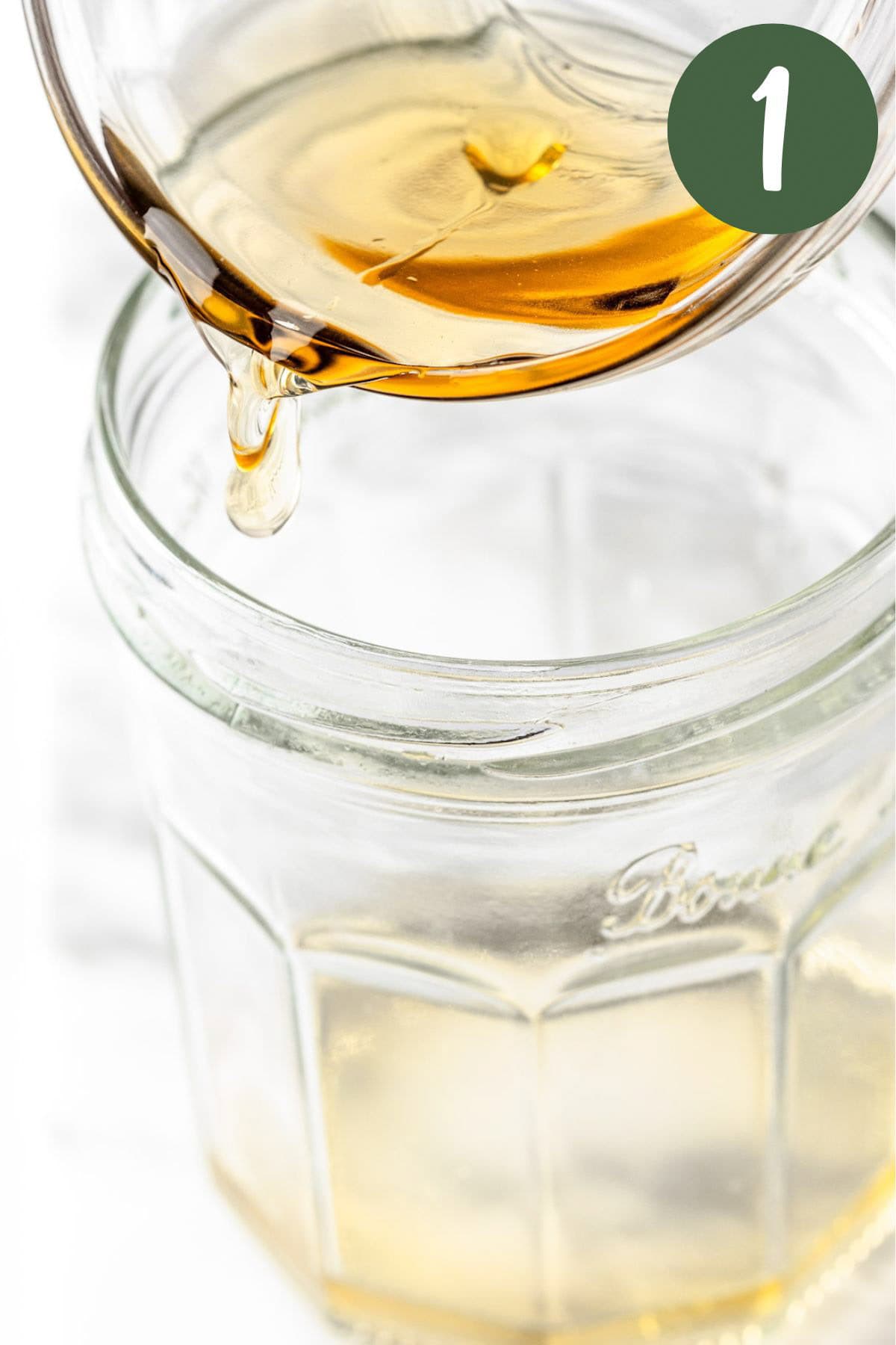 A process photo showing the apple cider vinegar being poured into a mason jar.