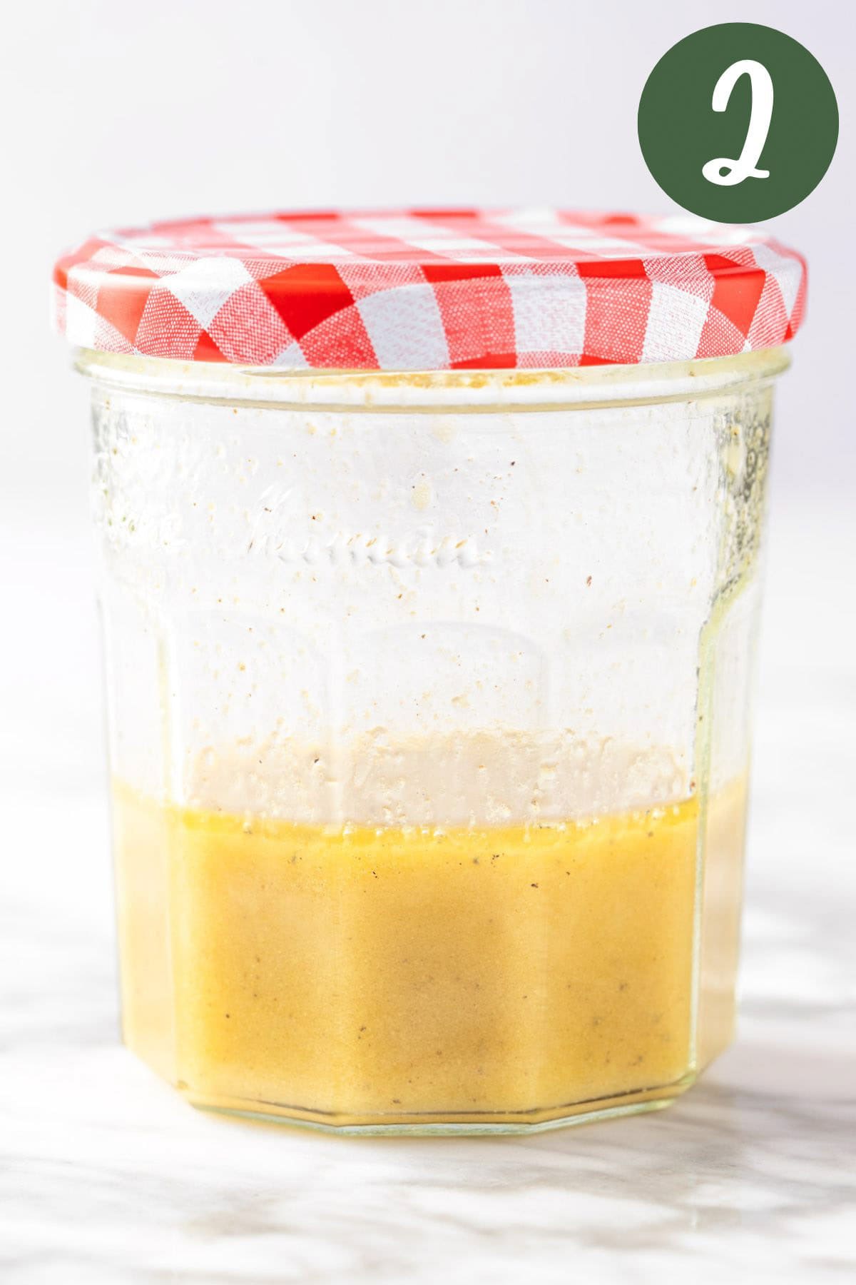 A process photo of the dressing ingredients shaken together in a mason jar, on a white background.