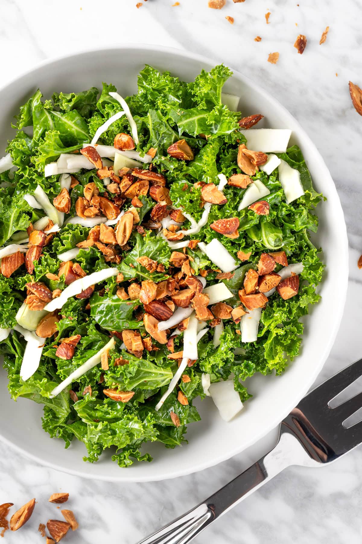 Overhead view of a bowl of Chick-Fil-A Kale Crunch salad made withe kale, roasted almonds, green cabbage and topped with an apple cider dijon vinaigrette.