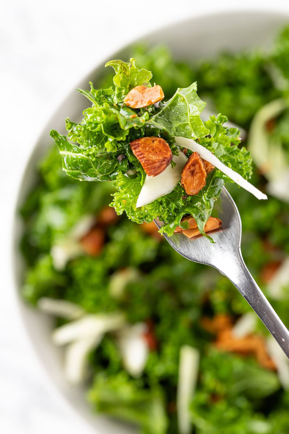 An up close forkful of kale crunch salad made with kale, green cabbage and almonds.