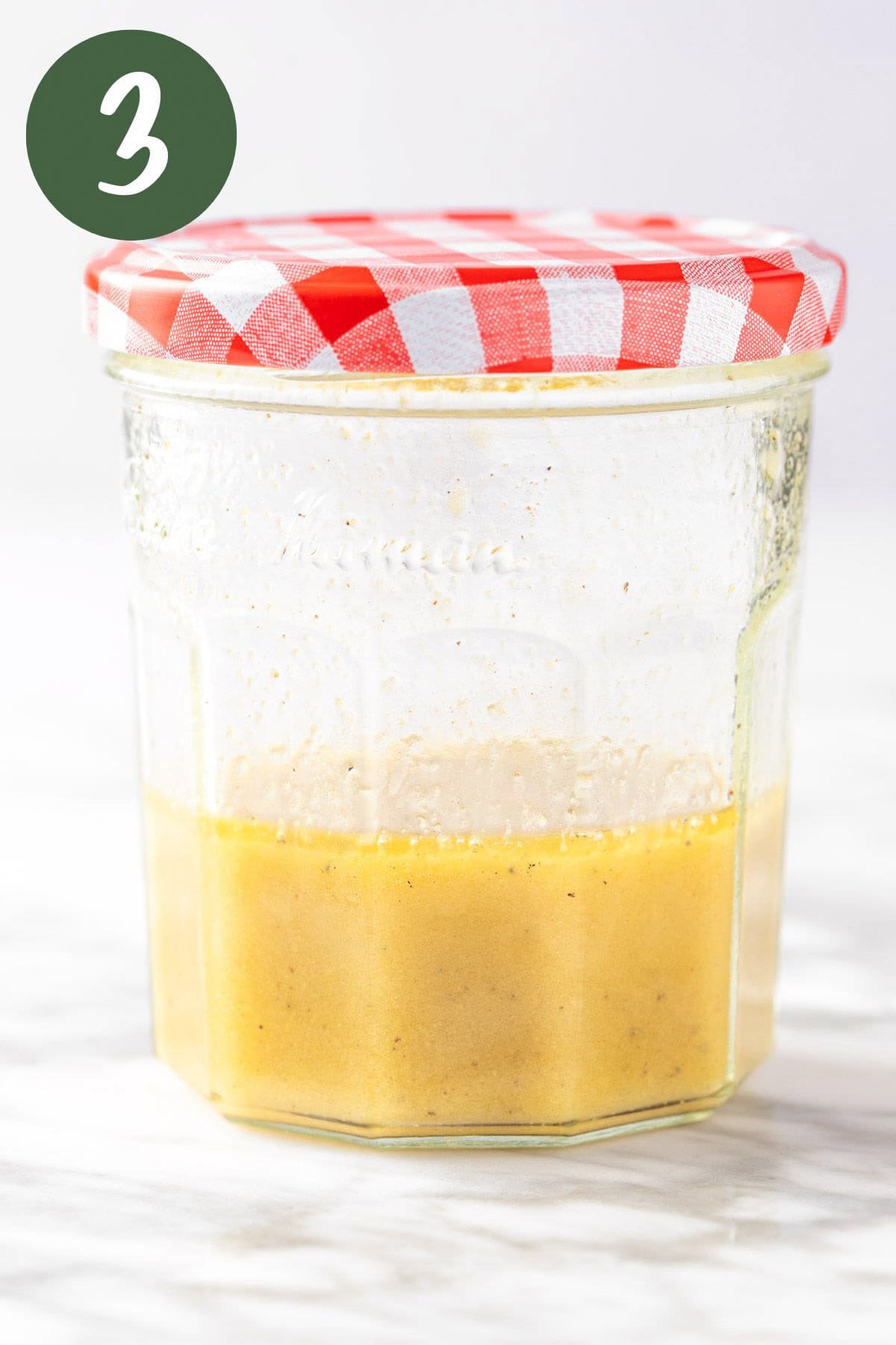 A process photo of the apple cider and dijon mustard vinaigrette mixed together in a mason jar.