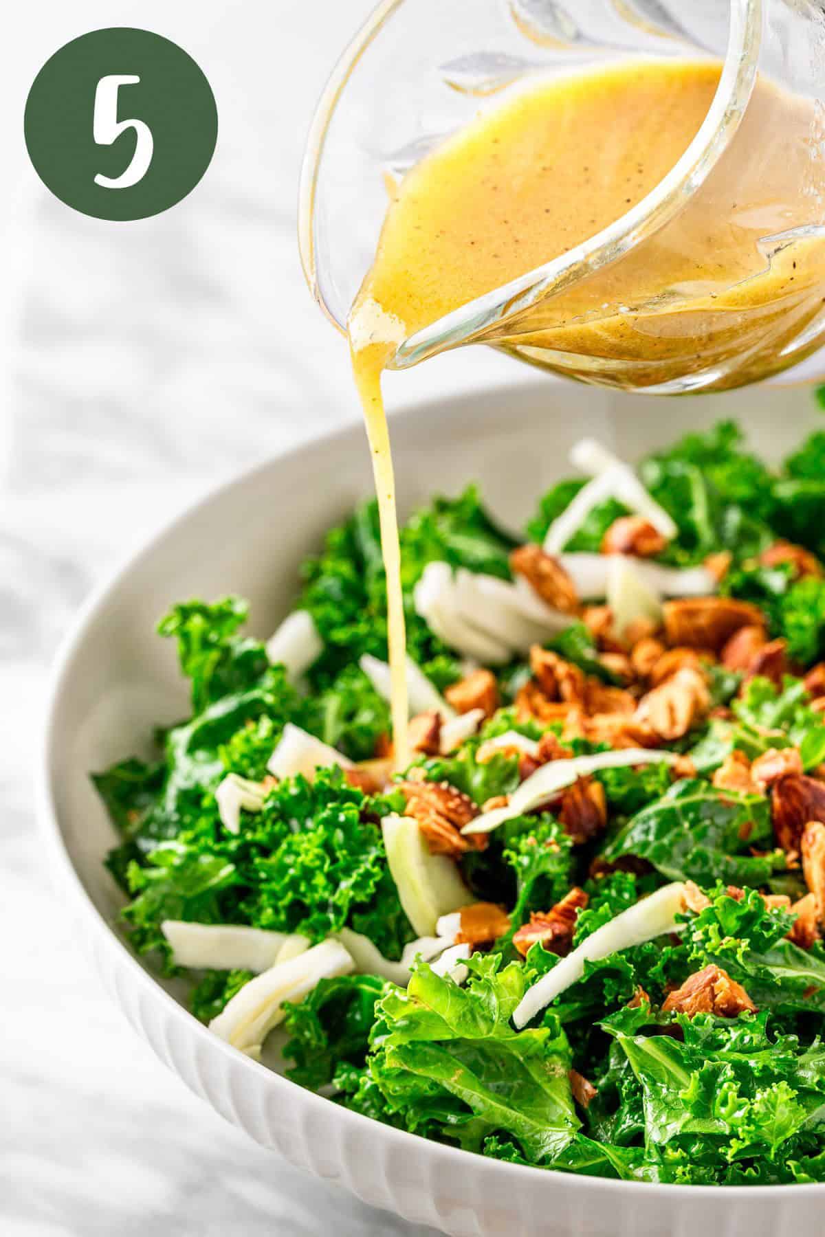 A process photo illustrating pouring the apple cider and mustard vinaigrette over the kale crunch salad.