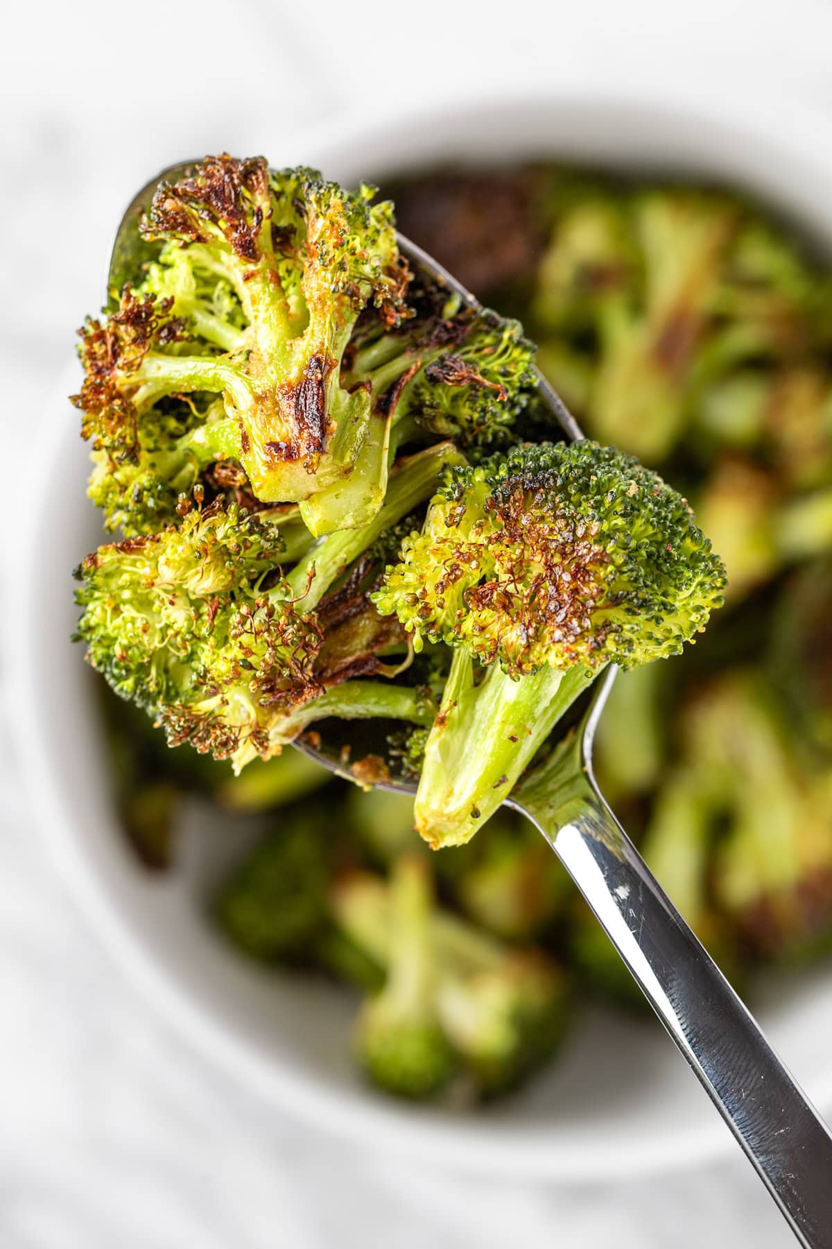 An up-close view of a spoonful of roasted Sweetgreen spicy broccoli.