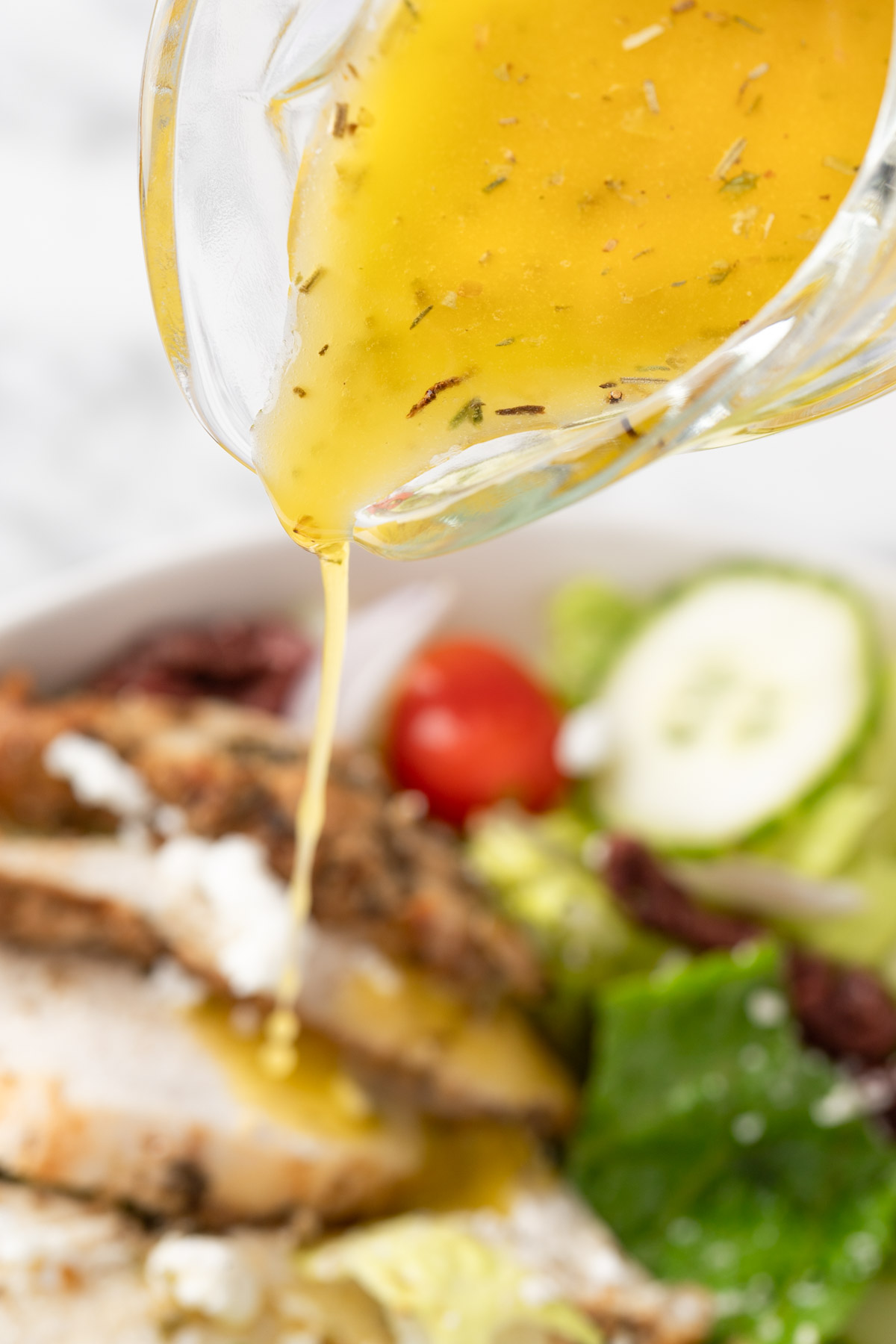 Pouring the Greek salad dressing over a salad.