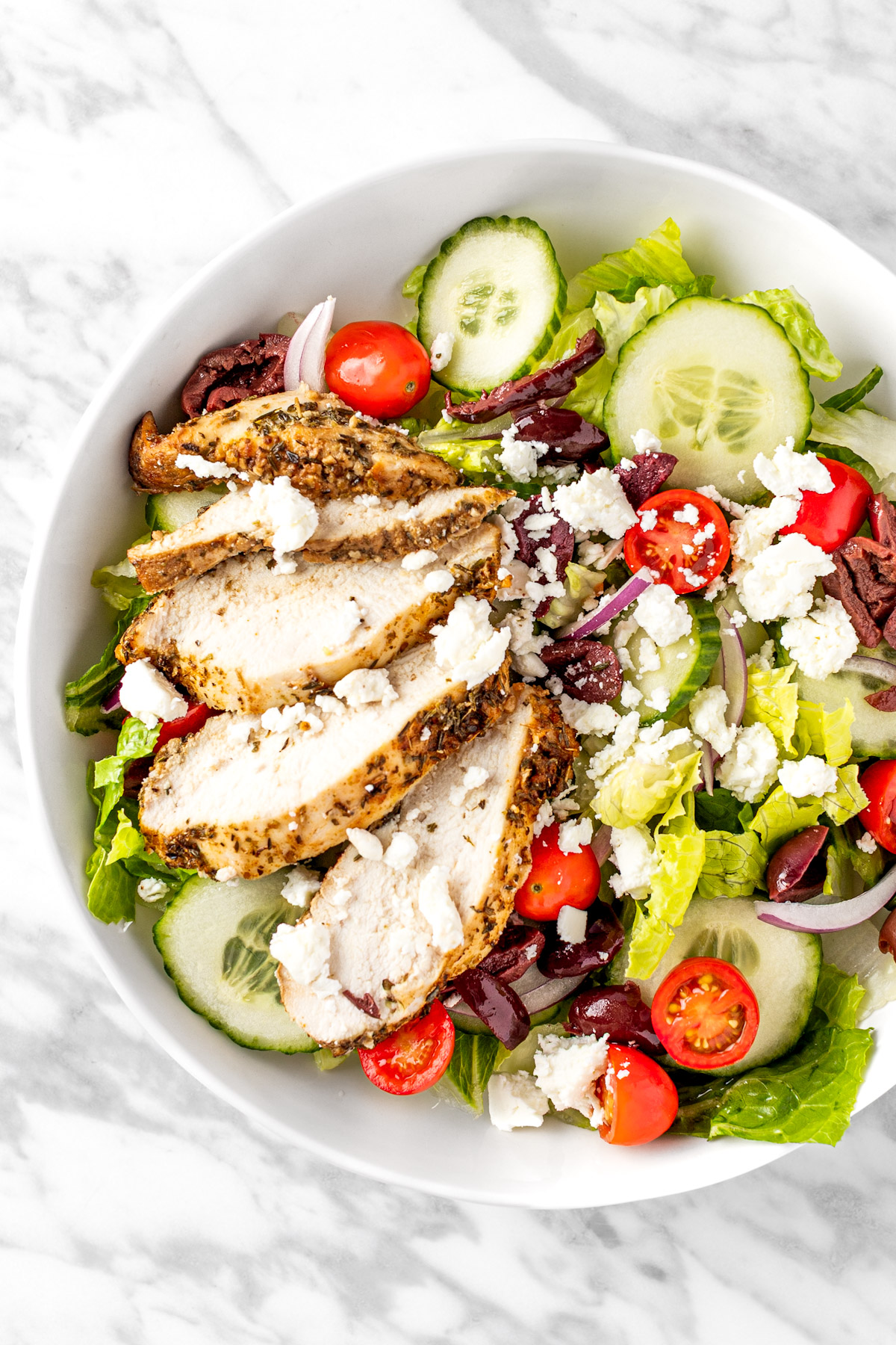 A Panera Bread Greek Salad made with chicken, feta, tomatoes, lettuce, red onions and olives.