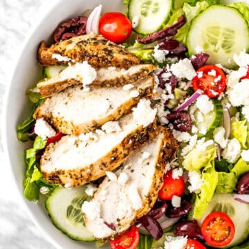 A Panera Bread Greek Salad made with chicken, feta, tomatoes, lettuce, red onions and olives.