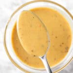 A close up view of a spoonful of yellow hot honey mustard sauce.