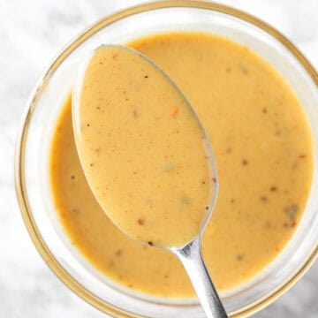 A close up view of a spoonful of yellow hot honey mustard sauce.