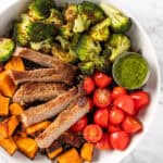 Overhead view of Sweetgreen Caramelized Steak Plate with steak, cherry tomatoes, sweet potatoes, wild rice and pesto vinaigrette.