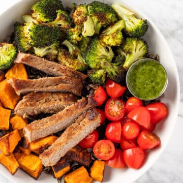 Overhead view of Sweetgreen Caramelized Steak Plate with steak, cherry tomatoes, sweet potatoes, wild rice and pesto vinaigrette.
